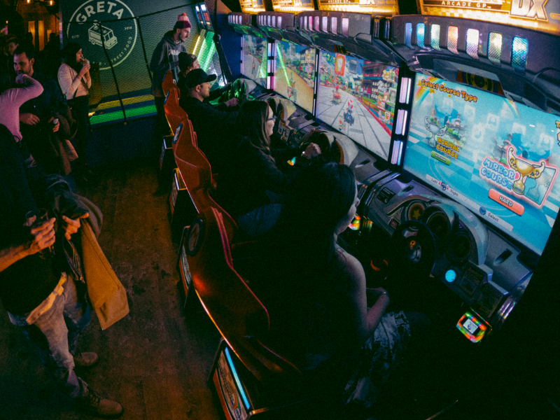 Guests playing arcade games and enjoying the entertainment at Greta arcade bar