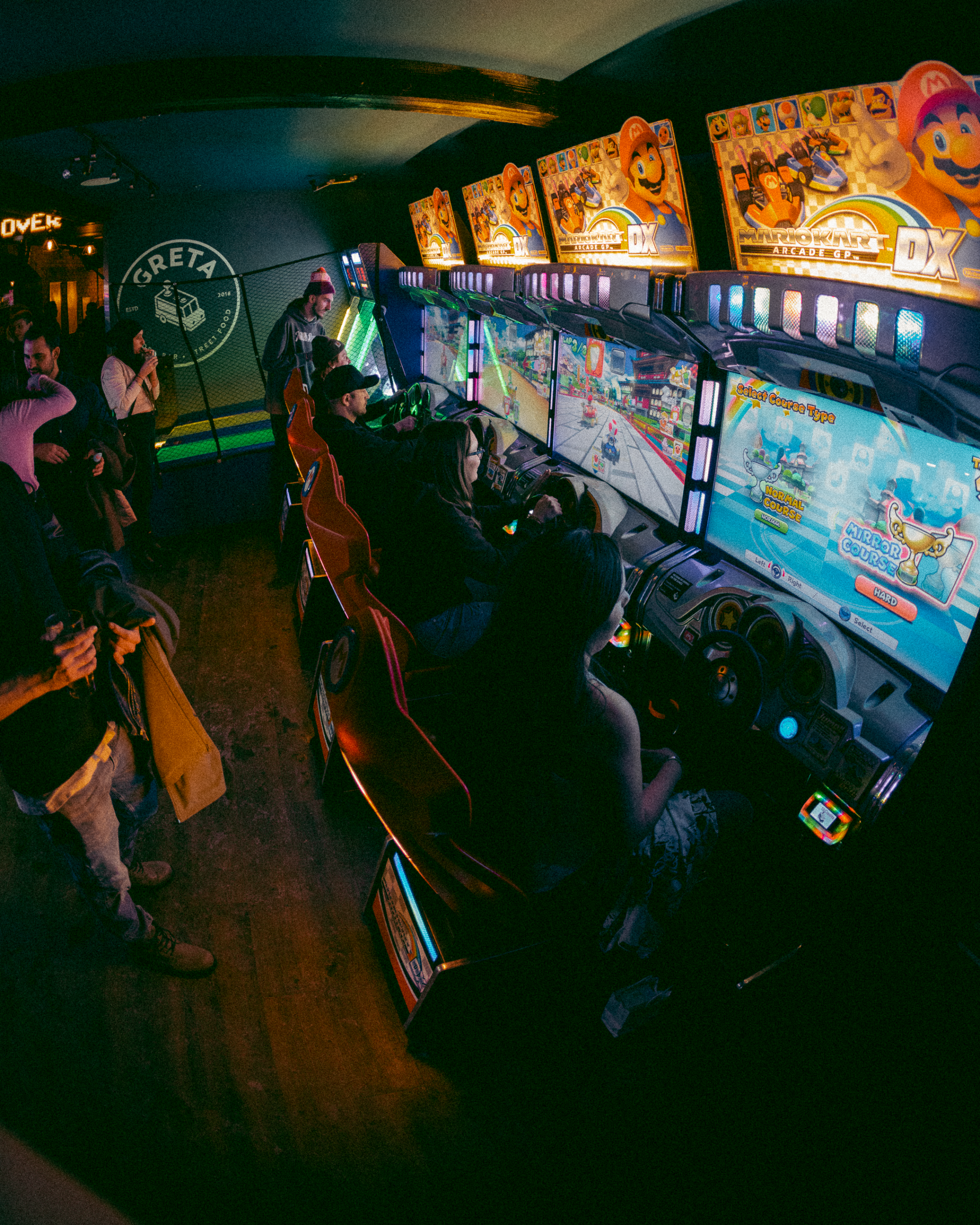 Guests playing arcade games and enjoying the entertainment at Greta arcade bar